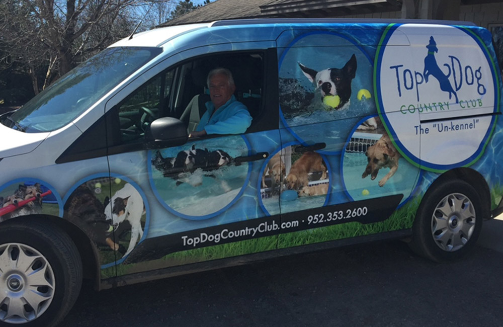 A person in a van with the Top Dog logo on the side